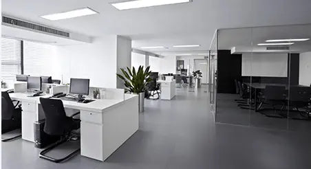 Modern office interior with clean white desks, computers, and glass-walled meeting room, showcasing professional office cleaning services for businesses.